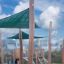Sun Shade Triangle 3x3x3 Nature (Robinia) installato in un'area giochi con supporti in legno.