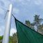 Sun Shade Triangle 5x5x5 Atlantis (Metal) installato su un palo all'aperto con cielo blu e alberi in 
