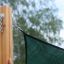 Sun Shade Triangle 5x5x5 Pioneer (Larchwood) fissato a un palo di legno.