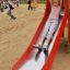 Bambino che scivola giù da Single Swing with Tower single slide in un parco giochi.