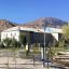 Attrezzature per fitness all'aperto in un parco con montagne e edifici sullo sfondo.