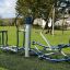 Attrezzatura fitness da esterno Set 8 installata in un parco giochi con erba verde e un albero sullo sfondo