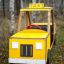 Auto giocattolo da parco giochi in legno giallo Taxi in un contesto boschivo.