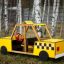 Gioco in legno giallo Taxi con design a scacchi parcheggiato sull'erba.