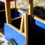 Camion giocattolo in legno con tetto rosso e lati blu per bambini.
