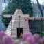 Wigwam wooden house in un contesto di area giochi con fiori rosa in primo piano