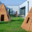 Wigwam wooden house su erba verde vicino a edifici moderni