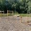 Attrezzatura da parco giochi all'aperto con Double Jump Bars su una superficie di cippato di legno con alberi sullo sfondo.