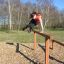 Donna che salta sopra Double Jump Bars in un parco.