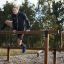 Atleta che scavalca l'attrezzatura fitness outdoor Double Jump Bars.