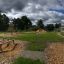 Parco fitness all'aperto con attrezzature per esercizi in legno in un'area aperta verde.