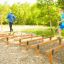 Due uomini che corrono su un percorso a ostacoli con travi di legno 'Hip Hop' in un parco giochi all'aperto.