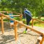 Bambini che giocano su Climb Obstacle wooden ladder in un parco giochi all'aperto.