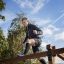 Uomo che scala Climb Obstacle wooden ladder in un parco all'aperto.