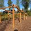 Scala in legno per percorso a ostacoli in un'area giochi all'aperto circondata da alberi.