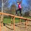 Donna che si arrampica su Climb Obstacle wooden ladder in un parco.