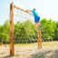 Ragazzo che si arrampica su V-shape Net Large climbing net in un parco giochi all'aperto.