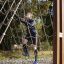 Uomo che si arrampica su V-shape Net Large climbing net in un parco giochi all'aperto.