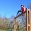 Donna che si arrampica su V-shape Net Large climbing net in un parco giochi all'aperto.