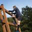 Uomo che si arrampica su Step And Climb wooden ladder all'aperto.