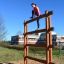 Donna che scala Step And Climb wooden ladder in un parco giochi all'aperto.