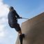 Uomo che si arrampica sul Climbing Ramp steel structure usando una corda.