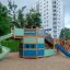 Majestic ship with slide in un parco giochi con colori verde e blu, circondato da alberi e edifici
