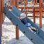 Bambino che scivola lungo lo scivolo grigio nel parco giochi Majestic ship with slide