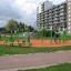 Bambini che giocano sul set da parco giochi Single Swing con attrezzature verdi e arancioni in un parco urbano