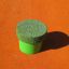 Palo elastico verde del set Jumping pegs (5 pcs.) su una superficie arancione.