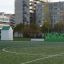 Casetta da gioco Shelter su un campo sportivo con edifici della città sullo sfondo.