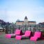 Lounge chair rosa posizionato su una terrazza in legno con lo skyline della città sullo sfondo.