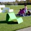 Sdraio verde su un prato del parco giochi con bambini che giocano sullo sfondo