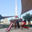 Attrezzatura da parco giochi Twister castle with slide in un contesto di parco urbano con il Burj Khalifa sullo sfondo