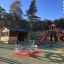 Twister castle with slide in un parco giochi con alberi circostanti e un riparo