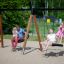 Double Swing (BNS 90cm) in uso in un parco giochi con famiglie che si divertono sulle altalene.