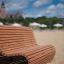 Sofa Wave da esterno su una spiaggia sabbiosa con ombrelloni ed edifici sullo sfondo.