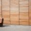 Moderno Sofa Wave in legno davanti a una parete di legno.