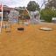 Attrezzatura da parco giochi Double Swing con due altalene, inclusa un'altalena a pneumatico, in un'area giochi sabbiosa.