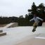 Skateboarder che esegue un trick su Jump-Ramp in uno skate park all'aperto.