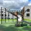 Attrezzatura da parco giochi New Age Fit MEDIUM con parete da arrampicata e scivolo in un contesto all'aperto.