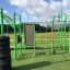Attrezzatura fitness all'aperto New Age Fit posizionata su un'area erbosa verde sotto un cielo parzialmente nuvoloso.