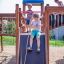 Tre bambini che giocano su un castello Space Station con uno scivolo in un parco giochi.