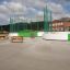 Arena sportiva polivalente con recinzione verde e area per sedersi.