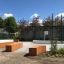 Campo sportivo all'aperto con recinzioni verdi, panchine in legno e canestro da basket, Multiarena.