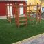 Chimpanzee wooden playhouse con scale da arrampicata e barre su erba artificiale verde.
