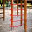 Casetta activity center in legno con strutture da arrampicata rosse in un parco giochi sabbioso