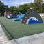 Dolphin Slide in un parco giochi con pavimentazione in gomma verde e alberi sullo sfondo