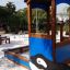 Villa with Orca single playhouse in un'area giochi sabbiosa con alberi circostanti.