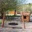 Set di altalene da parco giochi in legno BNS Single Swing Robinia 2 Posts accanto a una piccola casetta da gioco in legno.